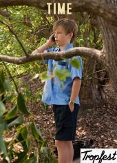 Nicholas Hamilton (as James) calmly talks on a cell phone in the woods.